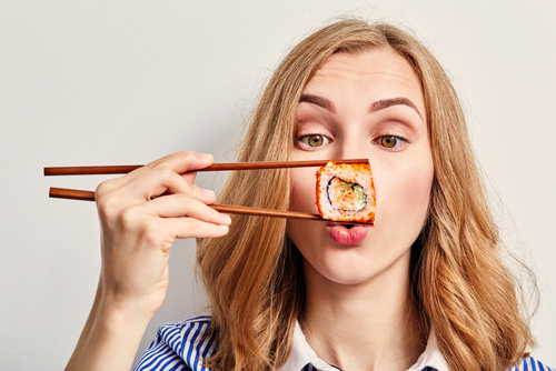 девушка держит суши около носа